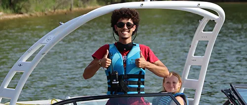 boy on a boat holding his thumbs up